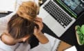 Stressed woman holding her head, staring down at her desk Fear, panic and leadership in business